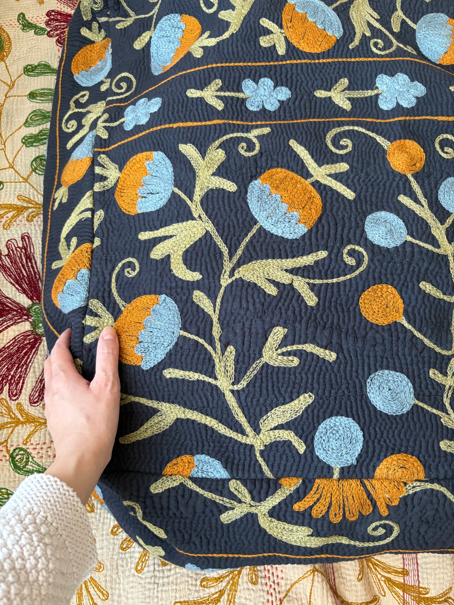 黒い生地にザクロやカーネーションが施されたスザニ刺繍カンタキルトのプフ