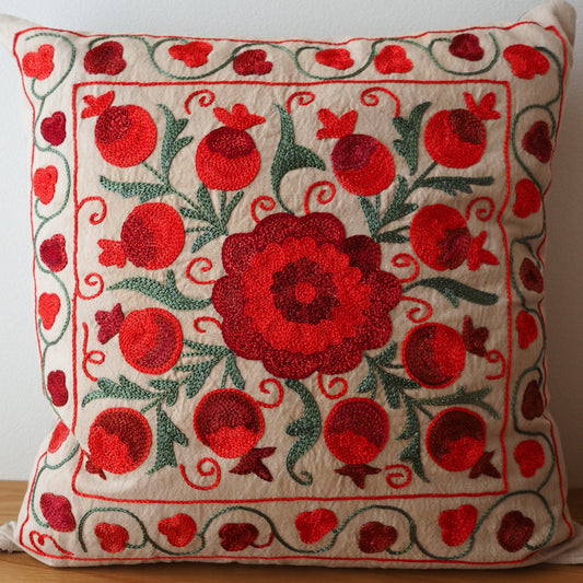 スザニ刺繍が施されたスザニクッションカバーです。ベージュの生地に赤いザクロのスザニ刺繍が映えて美しい1枚です